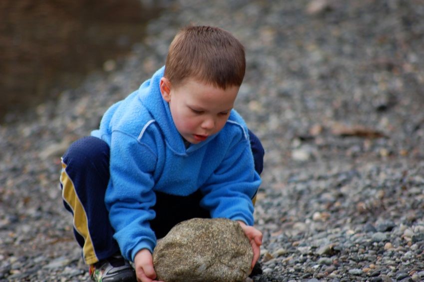 kid picking up big rock